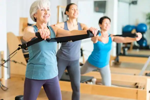 Toning Arms After 60: Empowering Womens Fitness Through Effective Weight Training 2 older woman doing weight training Lewes and resistance in the gym to tone upper arms